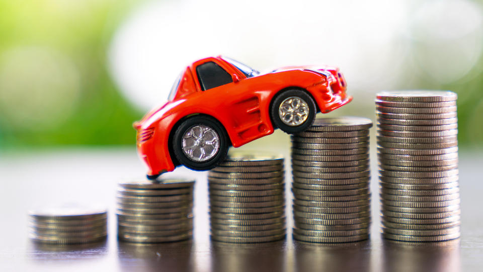 Car climbing a slope of coins, indicating an increase in costs.