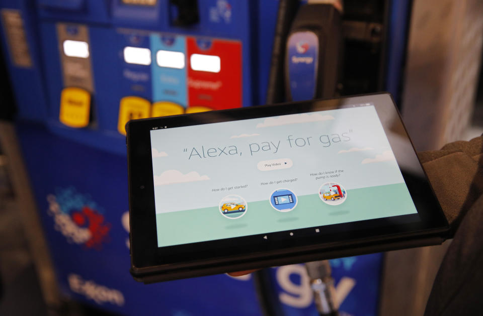 An employee holds a tablet showing a video demonstrating the Alexa pay for gas feature in the Amazon booth at the CES tech show, Wednesday, Jan. 8, 2020, in Las Vegas. (AP Photo/John Locher)