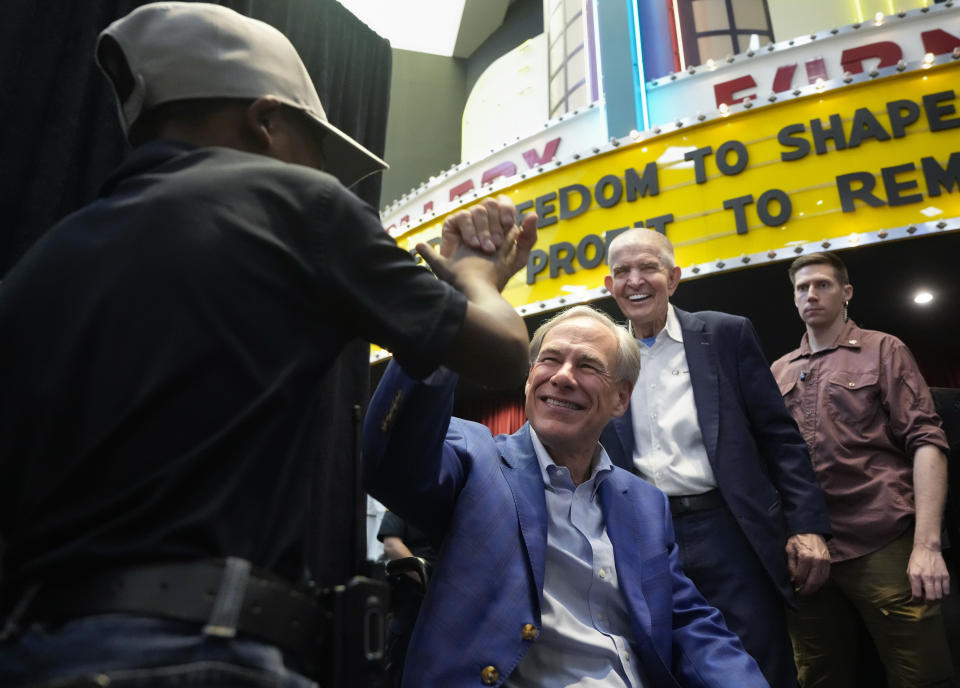 A kid, left, high-fives Gov. Greg Abbott after a press conference on Hurricane Beryl as Gallery Furniture Owner Jim "Mattress Mack" Mcingvale, second from right, smiles Sunday, July 14, 2024, at Gallery Furniture in Houston. (Yi-Chin Lee/Houston Chronicle via AP)