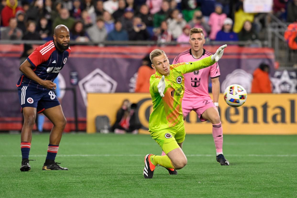 New England Revolution goalkeeper Henrich Ravas dives for the ball ahead of Inter Miami CF midfielder Julian Gressel and defender Andrew Farrell in the second half at Gillette Stadium.