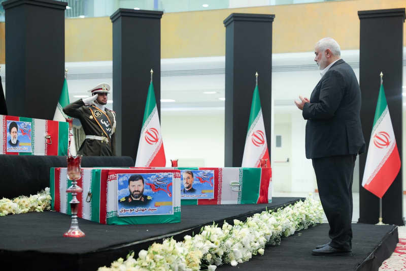 Hamas leader Ismail Haniyeh prays in front of the flag-draped coffins of Iran's late President Ebrahim Raisi, Foreign Minister Hossein Amir-Abdollahian, and others killed in a helicopter crash, which are being placed in a hall where heads of state and high officials will pay their respects before the burial ceremony. -/Iranian Presidency/dpa