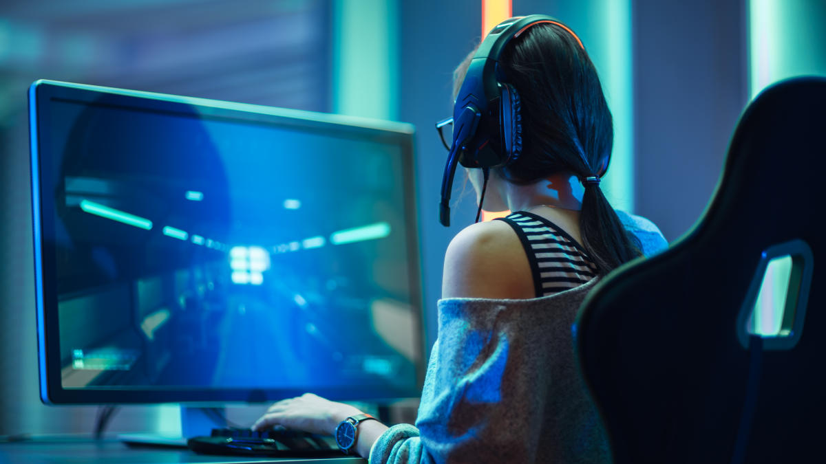 Girl in headphones plays a video game on the big TV screen. Gamer with a  joystick.