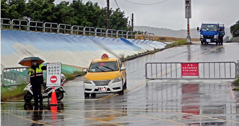 士林百齡橋附近河堤未設疏散門，車輛是由越堤道路進出，只要及早通知車主駛離，可以避免民眾的財產損失。圖為士林社子島的越堤道封閉，員警在入口處進行管制。（圖／報系資料照）