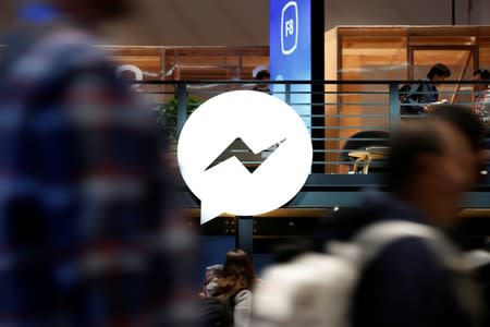 Attendees walk past a Facebook Messenger logo during Facebook Inc's annual F8 developers conference in San Jose, California