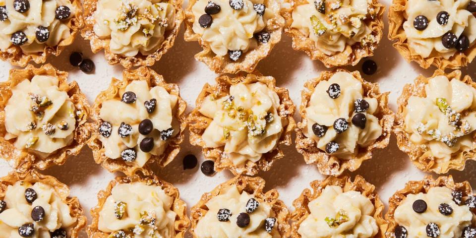 individual cannoli bites topped with chocolate chips, crushed pistachio and powdered sugar