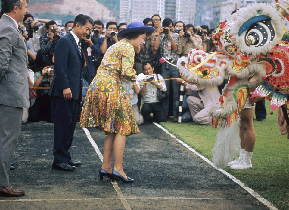 Queen Elizabeth II greets the front end of an ornate Chinese dragon in Hong Kong during the Royal Tour of 1975. (Hulton Archive/Getty Images) 