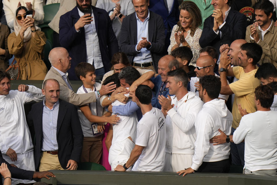 Spain's Carlos Alcaraz, center, is embraced by coaches, friends and family, as he celebrates in the players box after beating Serbia's Novak Djokovic to win the final of the men's singles on day fourteen of the Wimbledon tennis championships in London, Sunday, July 16, 2023. (AP Photo/Alastair Grant)
