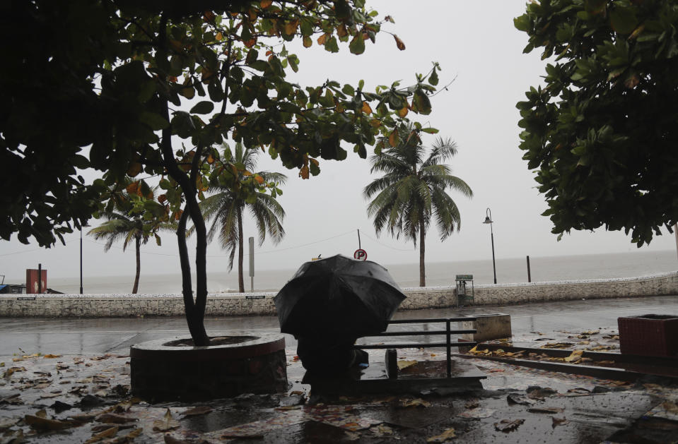 A man sit on a bench as it rains by the shores of the Arabian Sea in Mumbai, India, Wednesday, June 3, 2020. A storm in the Arabian Sea off India's west coast intensified into a severe cyclone on Wednesday, gathering speed as it barreled toward India's financial capital of Mumbai. Nisarga was forecast to drop heavy rains and winds gusting up to 120 kilometers (75 miles) per hour when it makes landfall Wednesday afternoon as a category 4 cyclone near the coastal city of Alibagh, about 98 kilometers (60 miles) south of Mumbai, India's Meteorological Department said. (AP Photo/Rafiq Maqbool)