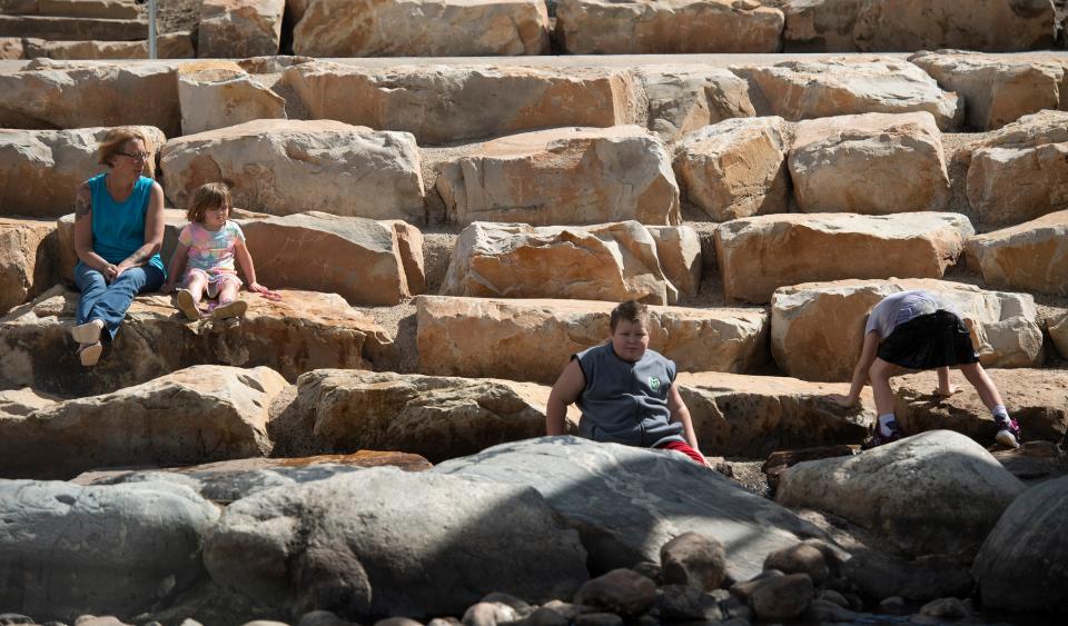 Jeara, a mother of four and a survivor of domestic violence, sits on a rock as she watches her children play in the water at Poudre Whitewater Park in Fort Collins. Jeara and her children left her husband on March 5, 2020,  the same day that Colorado saw its first reported case of the coronavirus. Now, she and her children live in a domestic violence shelter in the midst of a global pandemic.