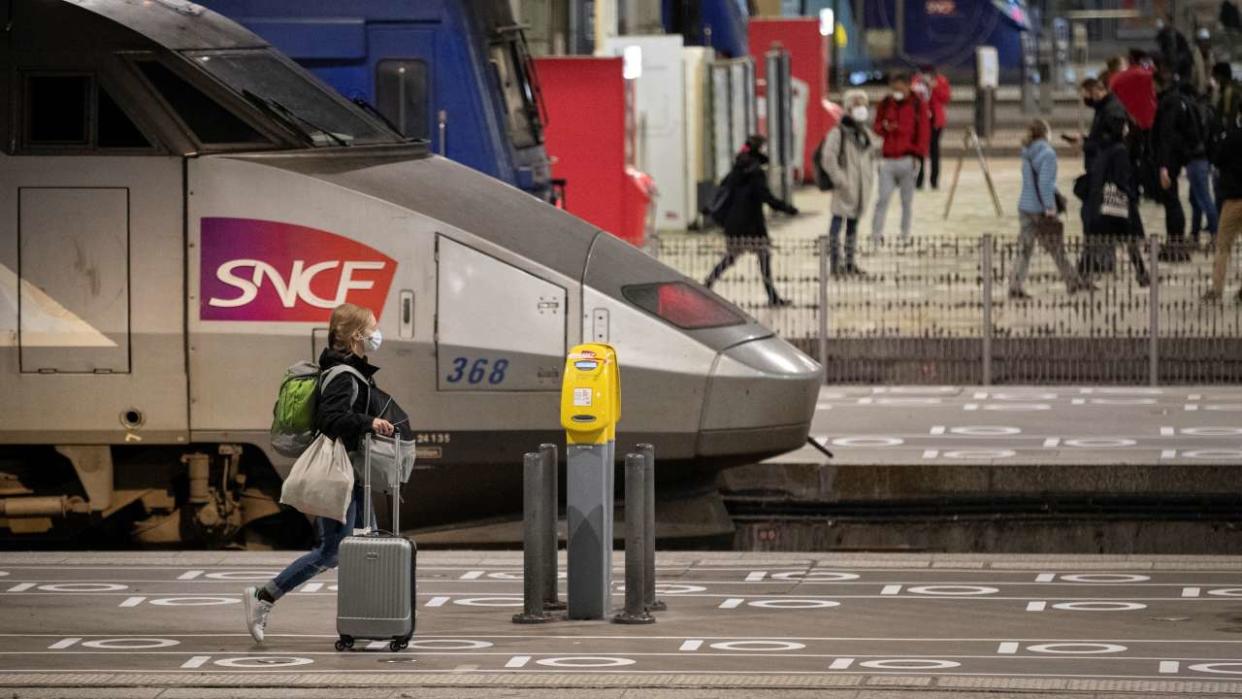 A traveller wearing protective mask walks past social distancing marks on the ground at the Gare Montparnasse train station in Paris on May 12, 2020 after France eased lockdown measures taken to curb the spread of the COVID-19 pandemic, caused by the novel coronavirus. (Photo by Thomas SAMSON / AFP)