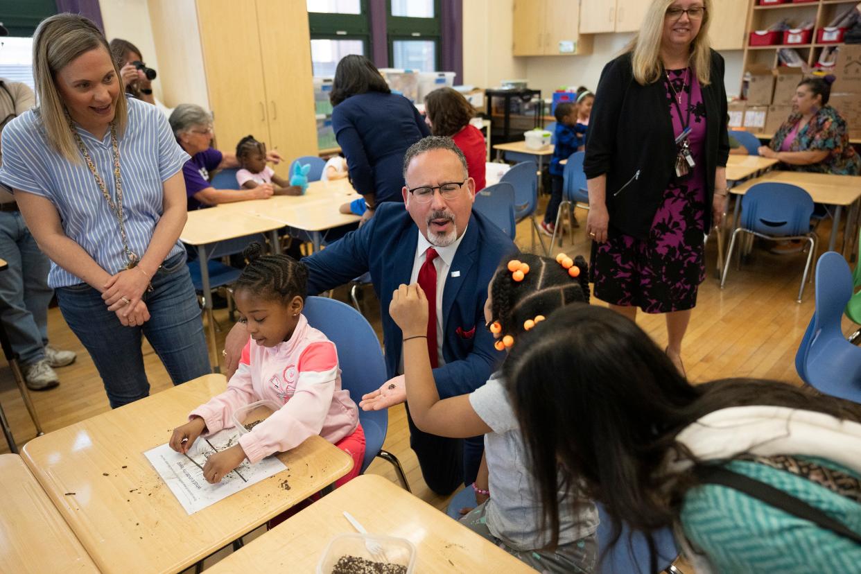 U.S. Secretary of Education Miguel Cardona looks at a toy ant that Zoe Spelhaug, 5, removed from her science project while teacher Sara Thomson watches in a pre-K classroom at Columbus City Schools' Avondale Elementary School in Franklinton.
