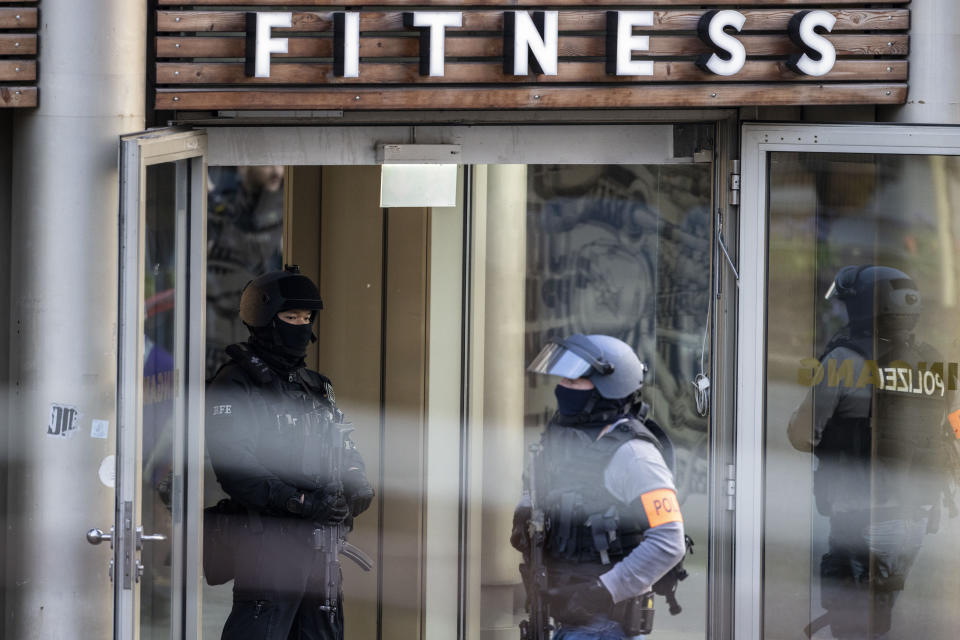 Armed police officers stay in front of a health club in Duisburg, Germany, Tuesday, April 18, 2023. German news agency dpa is quoting police as saying several people have been injured in an attack at a gym in the western city of Duisburg. Tuesday evening’s attack occurred in the old city of Duisburg and police asked residents to avoid the area. (Christoph Reichwein/dpa via AP)