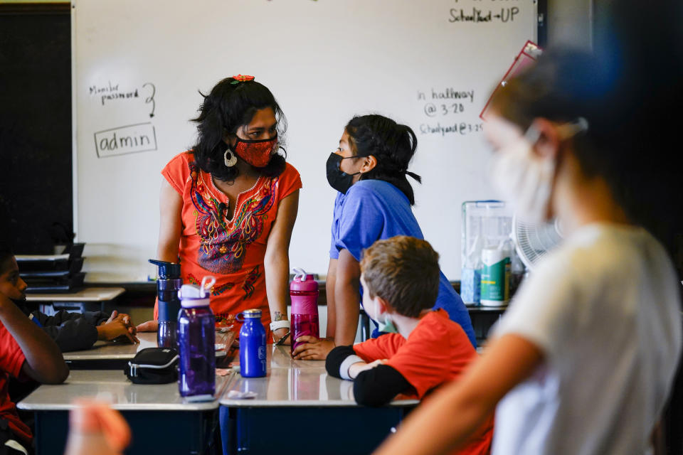 Student teacher Olivia Vazquez, standing, left, speaks with a student at the Eliza B. Kirkbride School in Philadelphia, Wednesday, Oct. 20, 2021. Vazquez is finishing up her last semester at Swarthmore College and hoping to help make sure immigrant students arriving in Philadelphia have a more supportive experience in school than she did growing up. (AP Photo/Matt Rourke)