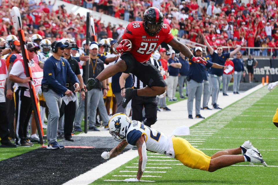 Texas Tech Red Raiders RB Tahj Brooks (28) hurdles West Virginia Mountaineers DB Davis Mallinger (27) in the first half at Jones AT&T Stadium and Cody Campbell Field.