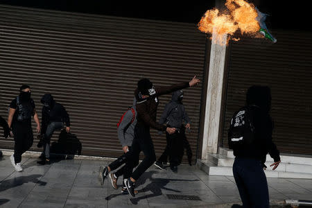 A hooded youth throws a petrol bomb to riot police during an anniversary rally marking the 2008 police shooting of 15-year-old student Alexandros Grigoropoulos, in Athens, Greece, December 6, 2017. REUTERS/Costas Baltas