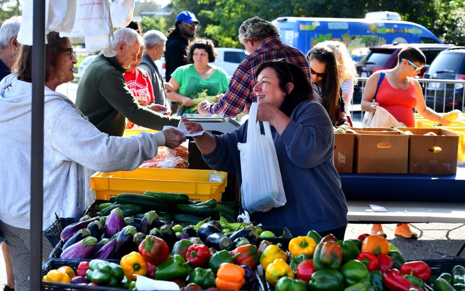 Paula Harper of Harper's Farm and Garden of Lancaster accepts payment for a bag of vegetables from Eileen Martell of Worcester at the REC Community Farmers Market at Beaver Brook Park on Friday.