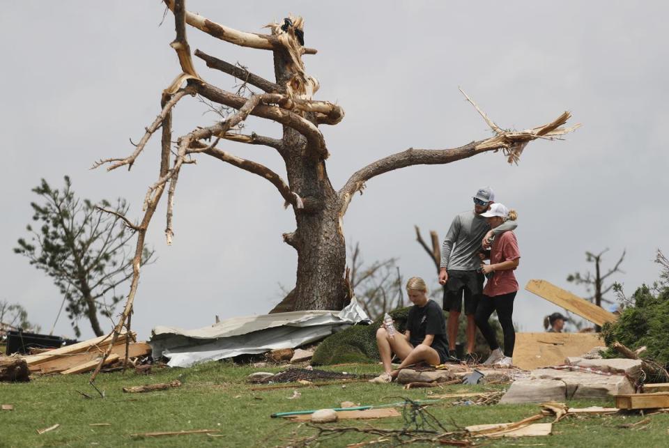 From left, Tyne Marshall sits on the ground next to Brett Homer and Cambrie Marshall, grand daughters of Ken and Mary Marshall, sho survives the tornado. Emergency personnel and Matador townspeople sift through the rubble Thursday morning, June 22, 2013, left after a tornado devastated the small town Wednesday night.