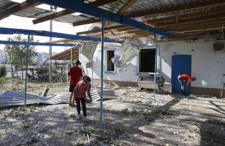 Local residents clean a yard after recent shelling on the outskirts of the southern coastal town of Mariupol September 7, 2014. REUTERS/Vasily Fedosenko