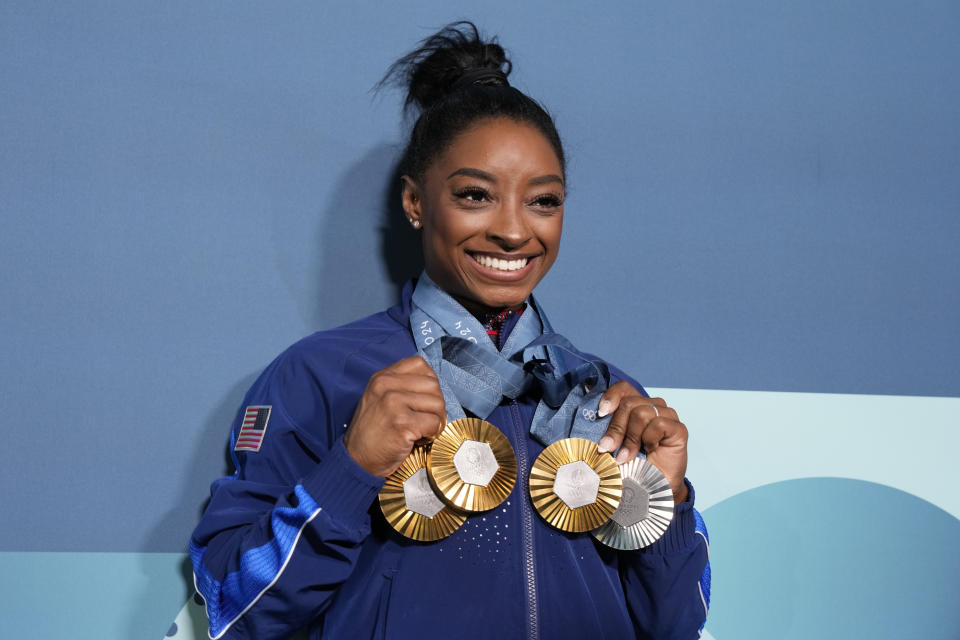 Simone Biles holds up her four medals from the 2024 Games.