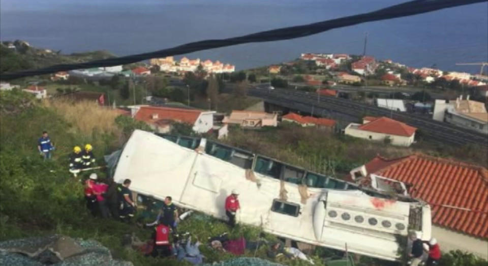 En esta imagen captada de un video, rescatistas laboran en el lugar donde un autobús turístico se estrelló en Canico, en la isla portuguesa de Madeira, el miércoles 17 de abril de 2019. (TVI vía AP)