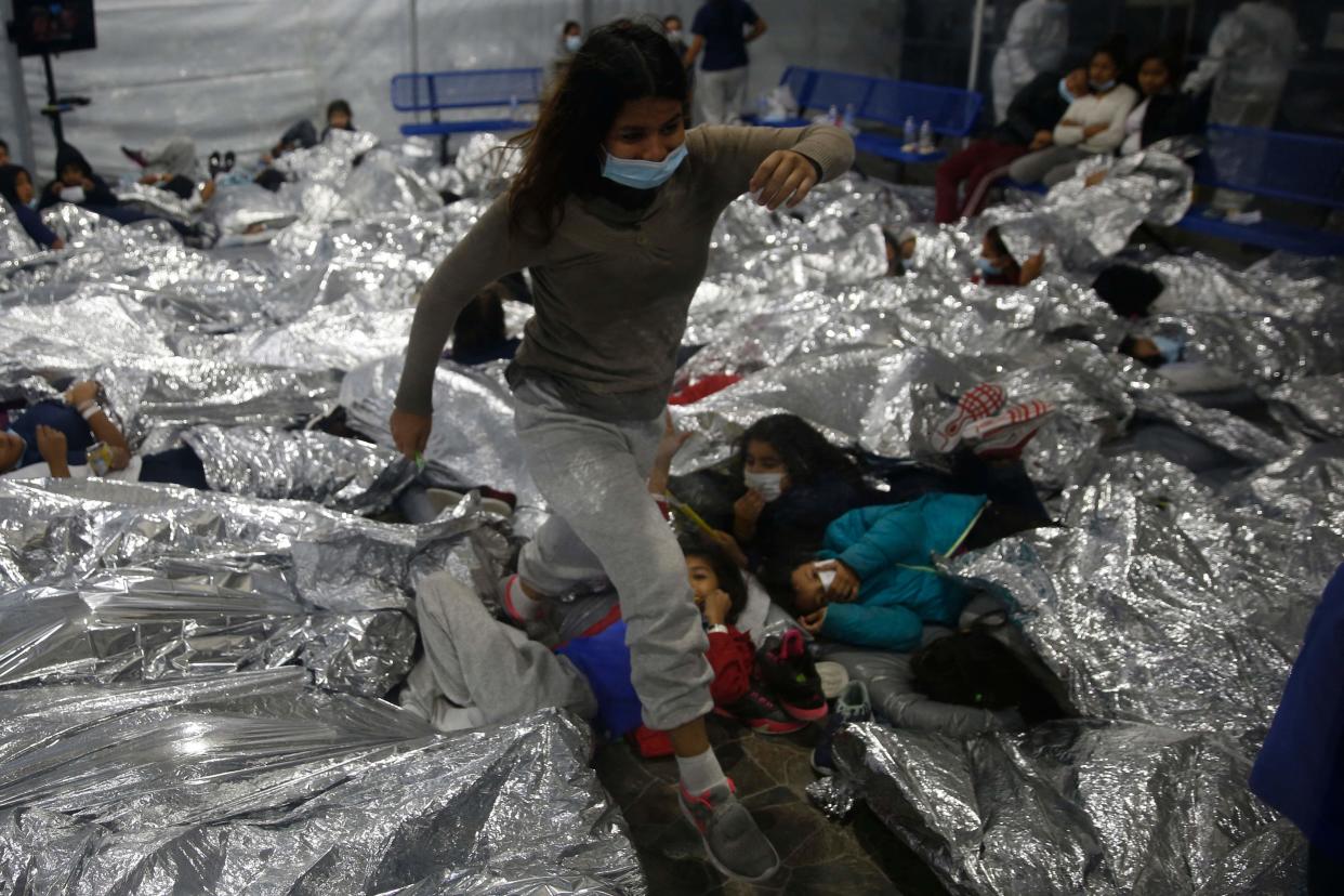 A young female minor walks over others as they lie inside a pod for females at the Donna Department of Homeland Security holding facility, the main detention center for unaccompanied children in the Rio Grande Valley run by the US Customs and Border Protection, (CBP), in Donna, Texas on March 30, 2021. - The minors are housed by the hundreds in eight pods that are about 3,200 square feet in size. Many of the pods had more than 500 children in them. The Biden administration on Tuesday for the first time allowed journalists inside its main detention facility at the border for migrant children, revealing a severely overcrowded tent structure where more than 4,000 kids and families were crammed into pods and the youngest kept in a large play pen with mats on the floor for sleeping. (Photo by Dario Lopez-Mills / POOL / AFP)