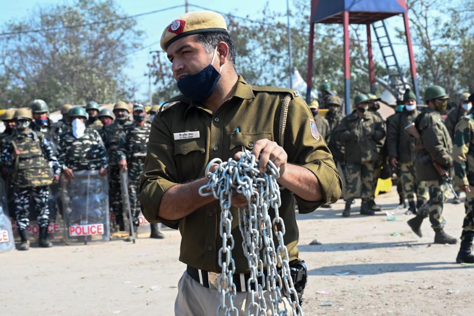 A police officer sets up road blocks at the Delhi-Haryana state border in Singhu on January 27, 2021, as farmers continue to demonstrate against the central government's recent agricultural reforms. (Photo by Money SHARMA / AFP) / The erroneous mention[s] appearing in the metadata of this photo by Money SHARMA has been modified in AFP systems in the following manner: [at the Delhi-Haryana state border in Singhu] instead of [at Singhu border in New Delhi]. Please immediately remove the erroneous mention[s] from all your online services and delete it (them) from your servers. If you have been authorized by AFP to distribute it (them) to third parties, please ensure that the same actions are carried out by them. Failure to promptly comply with these instructions will entail liability on your part for any continued or post notification usage. Therefore we thank you very much for all your attention and prompt action. We are sorry for the inconvenience this notification may cause and remain at your disposal for any further information you may require. (Photo by MONEY SHARMA/AFP via Getty Images)