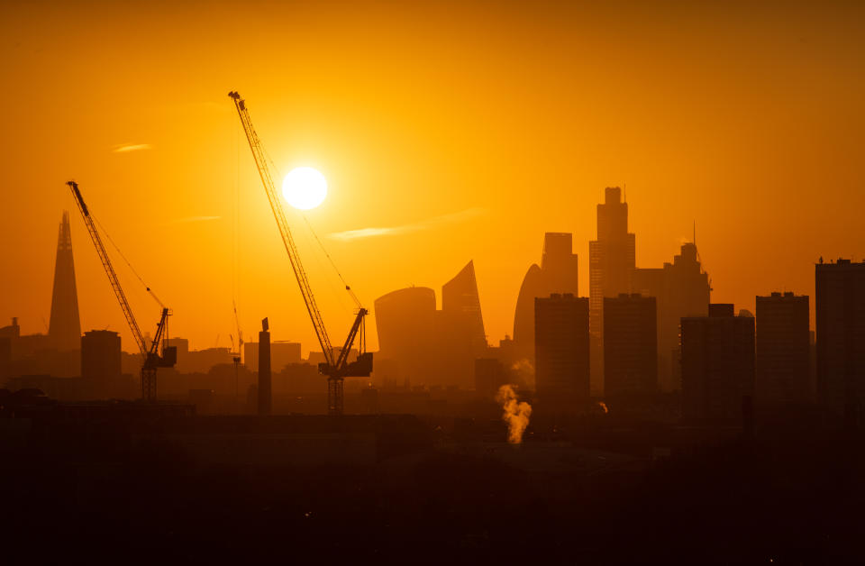 The sun sets behind tower cranes and the London skyline, including the Shard (left) and skyscrapers in the city financial district of London. PA Photo. Picture date: Tuesday January 21, 2020. Photo credit should read: Dominic Lipinski/PA Wire