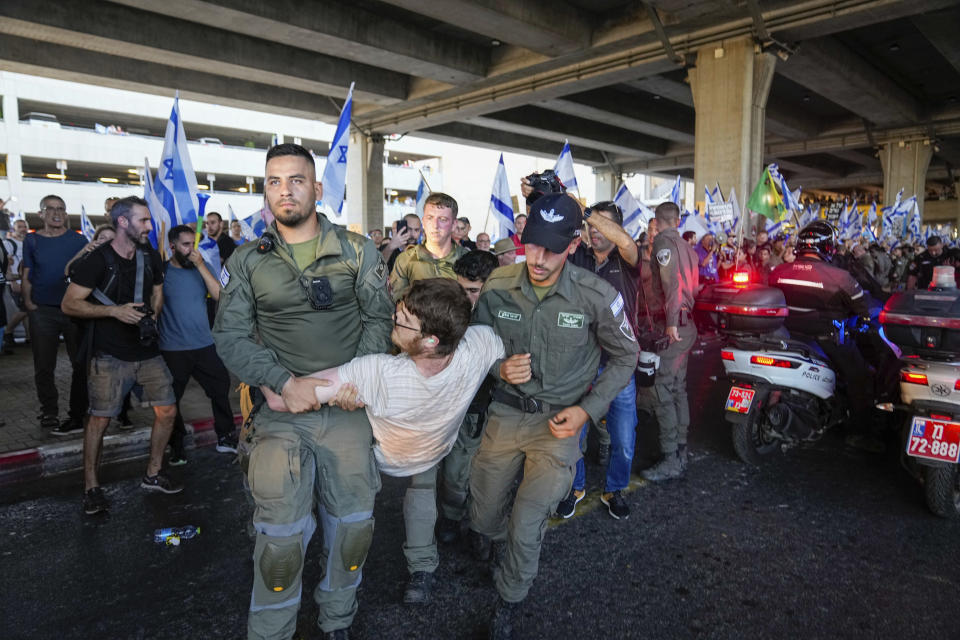 Israeli border police officers detain a demonstrator during a protest against plans by Prime Minister Benjamin Netanyahu's government to overhaul the judicial system, at Ben Gurion Airport in Lod, near Tel Aviv, Israel, Monday, July 3, 2023. Thousands of Israelis blocked traffic and snarled movement at the country's main international airport. (AP Photo/Ohad Zwigenberg)