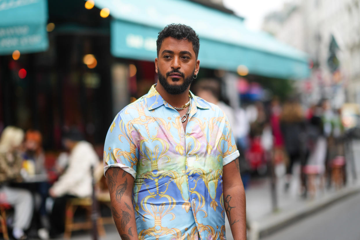 PARIS, FRANCE - JUNE 23: Slimane Nebchi, singer and winner of the fifth edition of The Voice France, wears a pastel colored shirt with short sleeves and printed patterns, outside BLUEMARBLE, during Paris Fashion Week - Menswear Spring/Summer 2022, on June 23, 2021 in Paris, France. (Photo by Edward Berthelot/Getty Images)