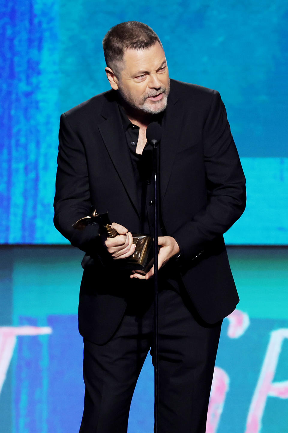 Nick Offerman en costume tenant son prix sur scène