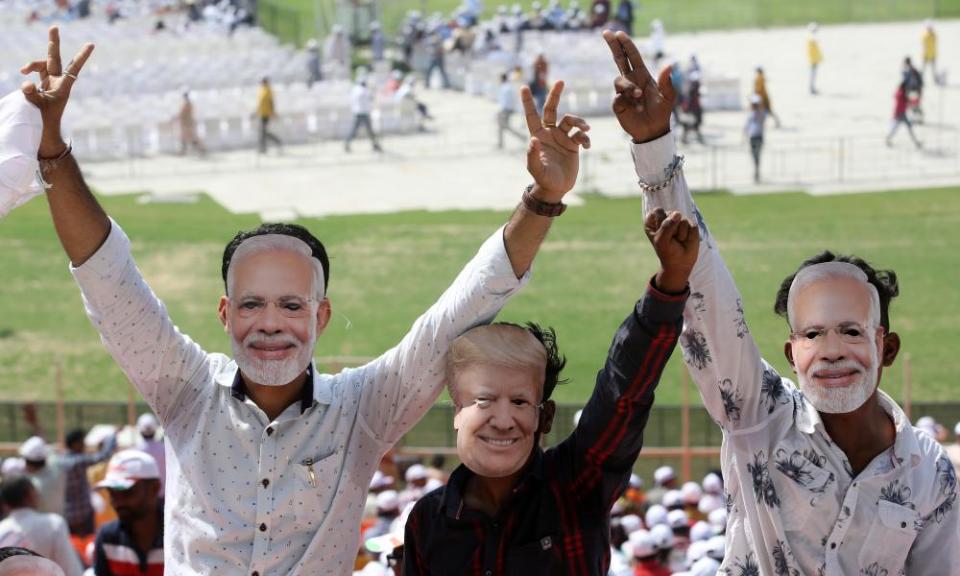 People wear masks of Modi and Donald Trump.