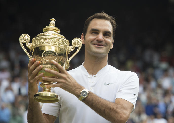 Roger Federer is seen here holding one of his record eight Wimbledon trophies aloft.