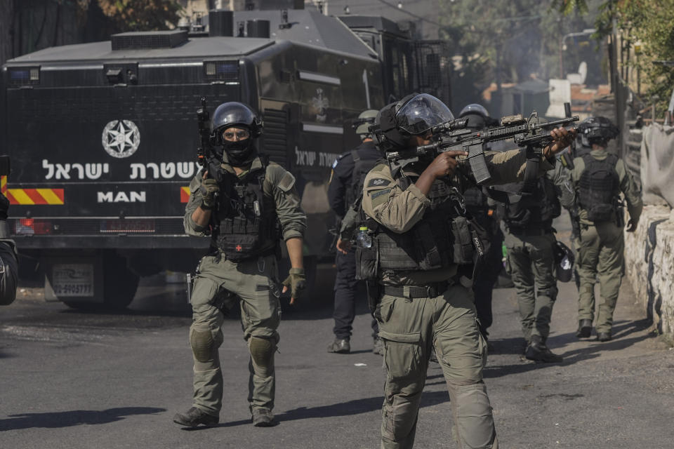 An Israeli security force member aims his gun during clashes with Palestinians in east Jerusalem, Friday, Oct. 13, 2023. At Al-Aqsa Mosque in Jerusalem, Israeli police had been permitting only older men, women and children to the sprawling hilltop compound for prayers, trying to prevent the potential for demonstration as tens of thousands attend on a typical Friday. (AP Photo/Mahmoud Illean)