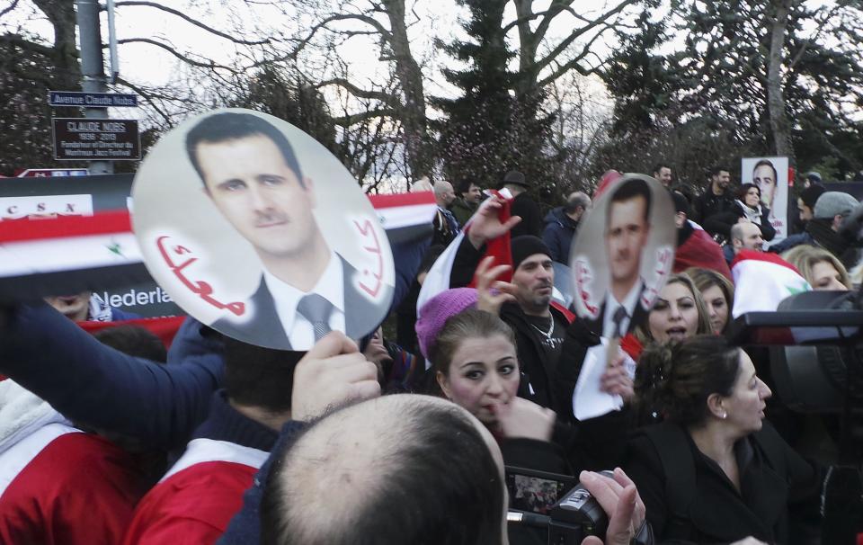 A pro-Assad demonstrator carry portraits of Syrian President Bashar al-Assad in front of the venue where the Syria peace conference is held, in Montreux January 22, 2014. Syria's government and opposition, meeting face to face for the first time at a U.N. peace conference, angrily spelled out their hostility on Wednesday as world powers also restated contrasting views on the future of President Bashar al-Assad. Signs read, "We are all with you". (REUTERS/ Kinda Makieh)