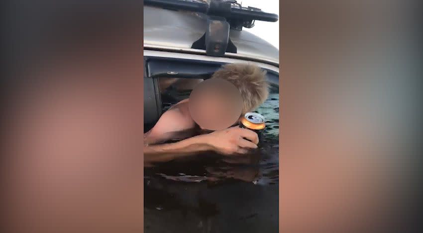 A man is seen clutching his can of drink as his 4WD is inundated with water. Source: Facebook