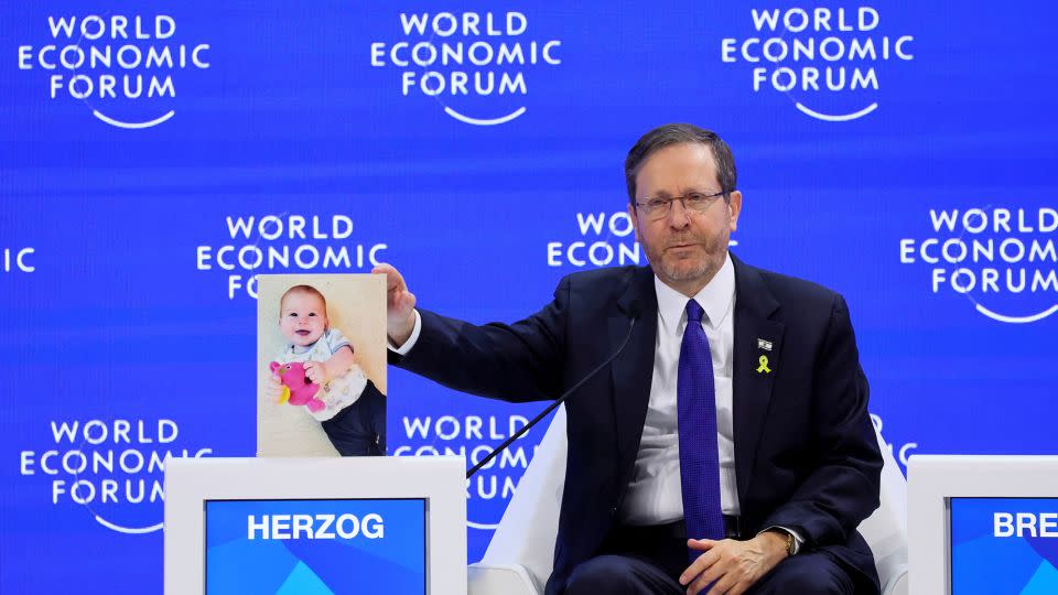 A picture of Kfir Bibas is placed next to Israeli President Isaac Herzog at the World Economic Forum in Davos. - Denis Balibouse/Reuters