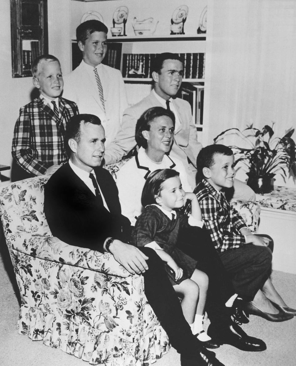 FILE - In this 1964 file photo, George H.W. Bush sits on couch with his wife, Barbara, and their children. George W. Bush sits at right behind his mother. Behind couch are Neil and Jeb Bush. Sitting with parents are Dorothy and Marvin Bush. The Kennedys had their New England coastal hideaway in Hyannis Port, a Camelot-like mystique and a political godfather in Joseph P. Kennedy. For the country's other political dynasty, the Bushes , it was a summer home in Maine and the West Texas oil patch that created a mix of Yale blue-blood and backcountry cowboy. Their patriarch was George H.W. Bush, a World War II hero, Texas congressman, the director of the CIA, vice president and eventually president. (AP Photo/File)