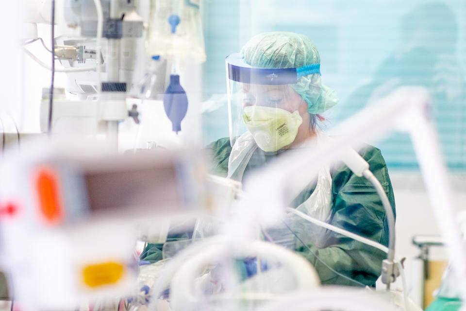 Eine Krankenpflegerin arbeitet in Schutzkleidung in einem Krankenzimmer auf der Intensivstation des Uniklinikums Essens. Foto: Marcel Kusch / dpa +++ dpa-Bildfunk +++