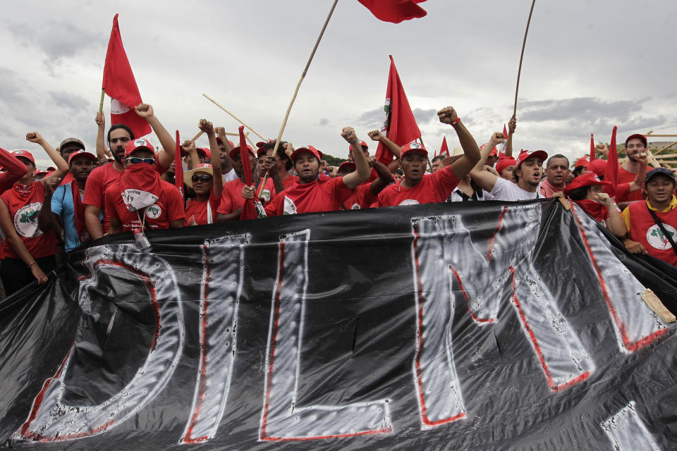 FILE - Demonstrators hold a banner that reads, "Dilma does nothing for land reform," as they shout slogans against Brazilian President Dilma Rousseff, in front of the presidential palace during a march organized by the Rural Workers Landless Movement in Brasilia, Brazil, Feb. 12, 2014. (AP Photo/Eraldo Peres, File)