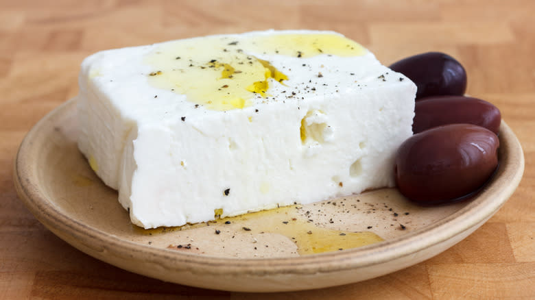 block of Greek feta with kalamata olives on a ceramic plate