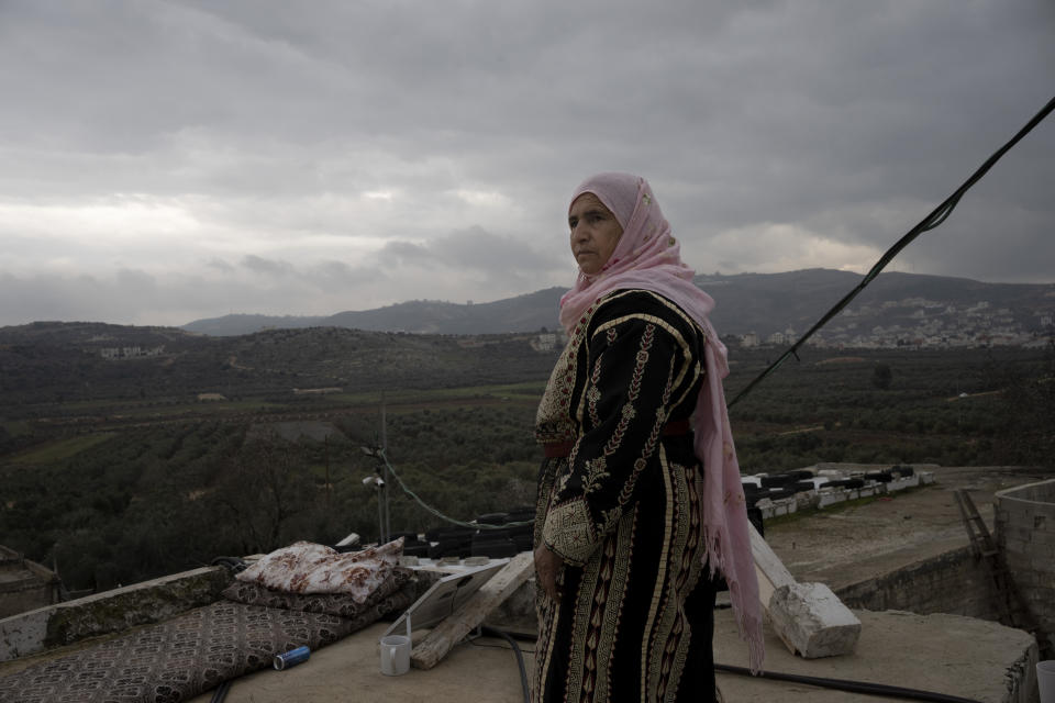 Amal Abu Awad, a Palestinian mother of nine, stands on her roof beside a sleeping mat used by a family member on an overnight guard shift, in the West Bank town of Turmus Aya, in close proximity to the Jewish settlement of Shilo, Thursday, Feb. 16, 2023. Her home and family are regularly attacked by settlers. Israel's new ultranationalist government declared last week that it would legalize 10 unauthorized outposts in the occupied West Bank. The rare move intensified the country's defiance of international pressure and opened an aggressive new front of Israeli expansion into the West Bank, which Israel captured in the 1967 Mideast war. (AP Photo/ Maya Alleruzzo)