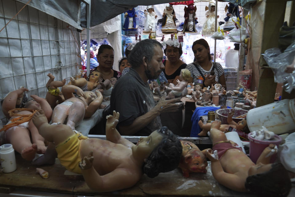 Maximino Vértiz Quintanilla repara la estatua del niño Dios de un cliente dentro de su tienda en preparación para la fiesta del "Día de la Candelaria" en la Ciudad de México, el miércoles 25 de enero de 2023. (AP Foto/Marco Ugarte)