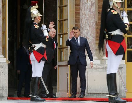 French President Emmanuel Macron (R) and Russian President Vladimir Putin wave during a meeting at the Chateau de Versailles near Paris, France, May 29, 2017. REUTERS/Alexander Zemlianichenko/Pool