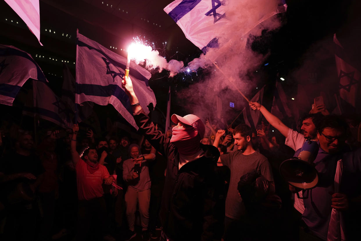 Israelis opposed to Prime Minister Benjamin Netanyahu's judicial overhaul plan block a highway during a protest after the Israeli leader fired his defense minister, in Tel Aviv, Israel, Monday, March 27, 2023. Defense Minister Yoav Gallant had called on Netanyahu to freeze the plan, citing deep divisions in the country and turmoil in the military. (AP Photo/Ohad Zwigenberg)