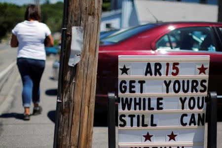 A pedestrian walks past a sign reading "AR15 Get Yours While You Still Can" outside the IDC Firearms gun shop in Clinton, Massachusetts, U.S. June 21, 2016. REUTERS/Brian Snyder/File Photo