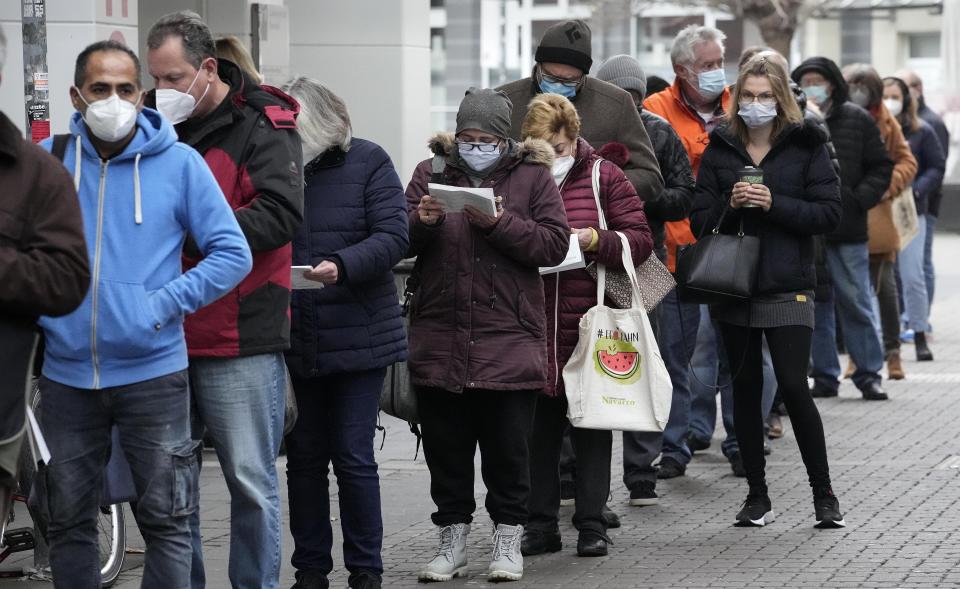 People queue in front of a vaccination center to get vaccinated against the coronavirus in Duesseldorf, Germany, Monday, Dec. 6, 2021. (AP Photo/Martin Meissner)