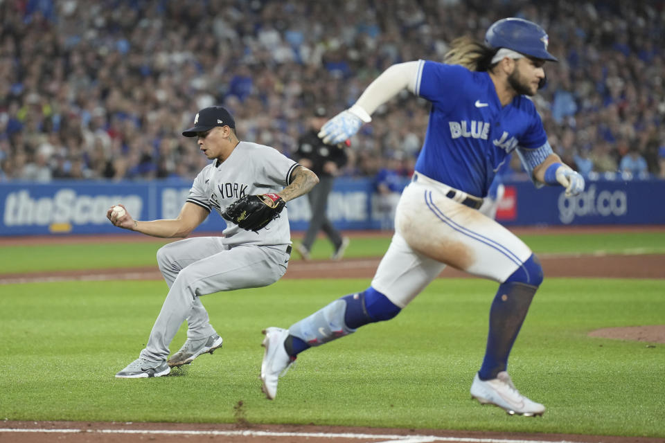 New York Yankees relief pitcher Jonathan Loaisiga, left, fields the ball to make a throw to first to put out Toronto Blue Jays' Bo Bichette, right, during seventh-inning baseball game action in Toronto, Monday, Sept. 26, 2022. (Nathan Denette/The Canadian Press via AP)