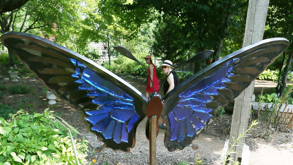 Visitors look at the Blue Mountain Swallowtail sculpture in the "Glass in Flight" exhibition by Alex Heveri at Reiman Gardens.