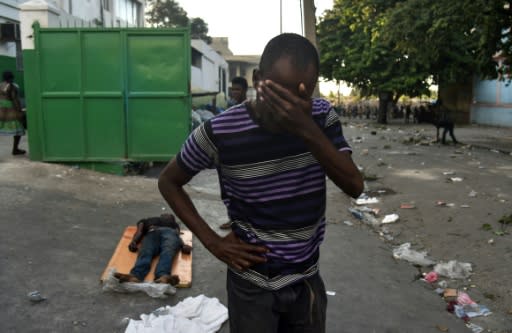 A man cries next to the body of a dead youth shot during clashes between Haitian police and demonstrators near the National Palace in Port-au-Prince, on February 9, 2019
