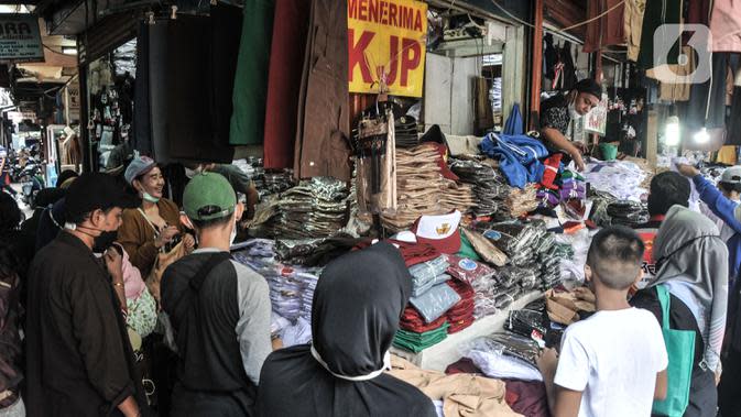 Pedagang melayani pembeli seragam sekolah di Pasar Mester Jatinegara, Jakarta Timur, Senin (3/1/2022). Salah satu pedagang mengungkapkan penjualan seragam sekolah mengalami peningkatan 50 persen seiring pemberlakuan PTM di Jakarta yang kembali digelar 100 persen. (merdeka.com/Iqbal S. Nugroho)